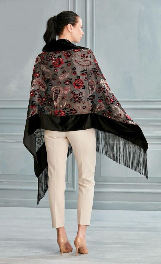 Woman wearing a floral patterned shawl with fringe on a light gray background