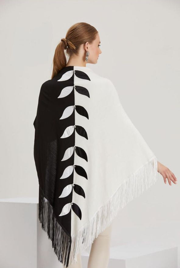 Woman wearing a black and white patterned shawl with fringe on a white background