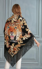 Woman wearing a decorative shawl with a tiger design against a gray wall.